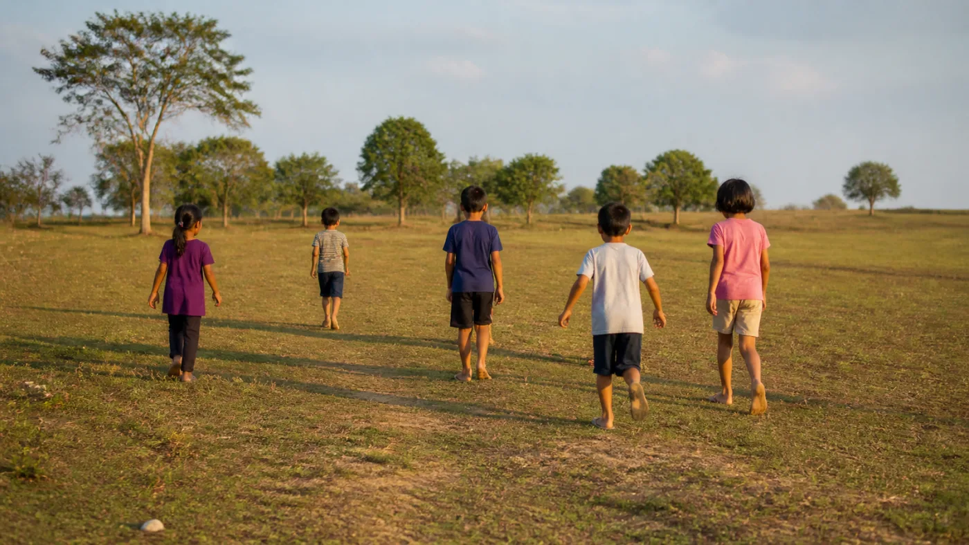 Children walking together in bright daylight, seen from a distance.